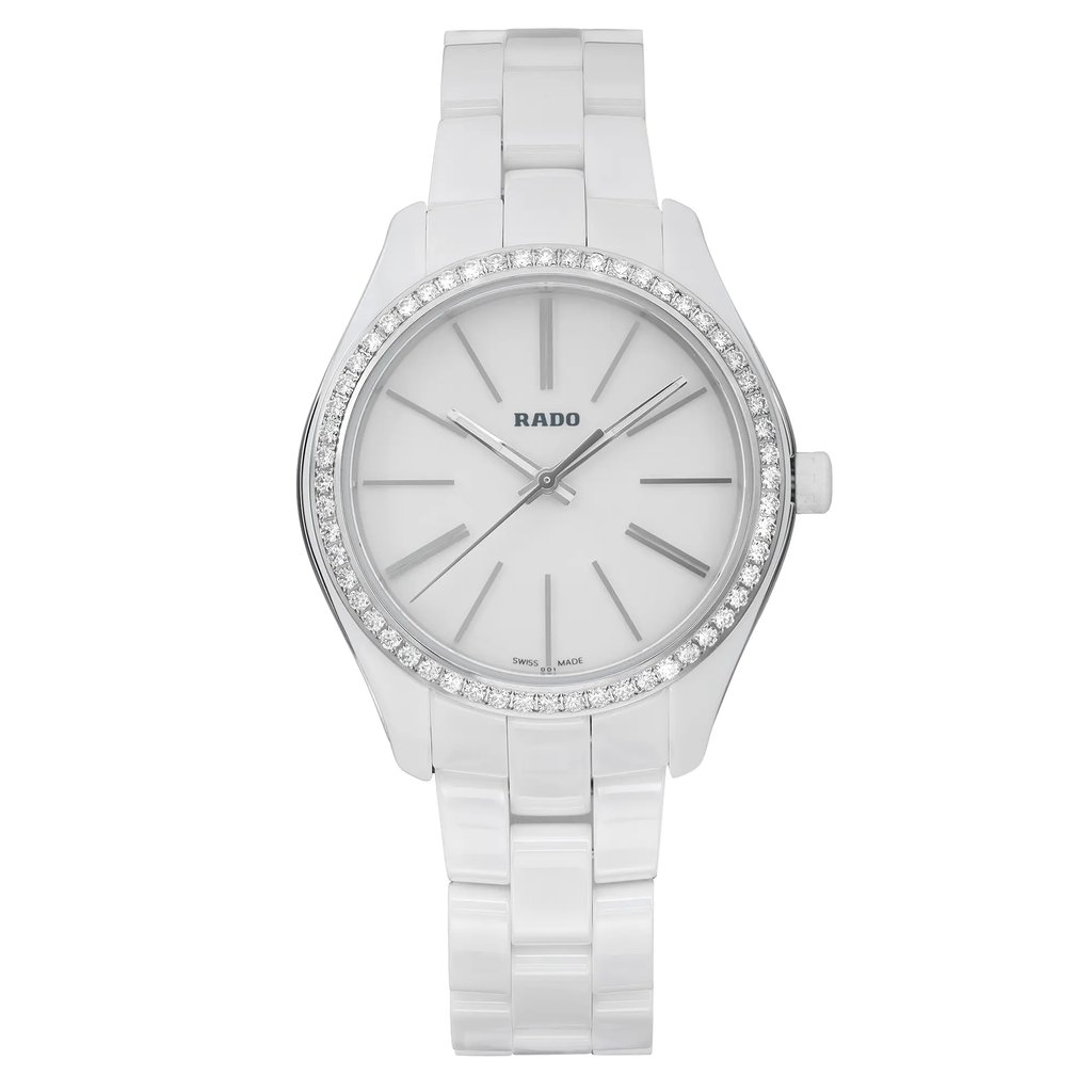 An image of an unworn Rado wristwatch for women in a casual style, presented in a full frontal view. The watch features a round white dial with non-numeric hour marks and stick indexes, as well as a seconds hand and luminous hands. It has a gray diamond bezel and the band is made of white ceramic with a steel/cemaric case. The watch is positioned centrally with the band partially extended, creating a slight curve at the bottom, against a neutral background. Distance from the view is close enough to clearly show the details of the watch face and band. The condition is excellent, indicating the watch is unworn.