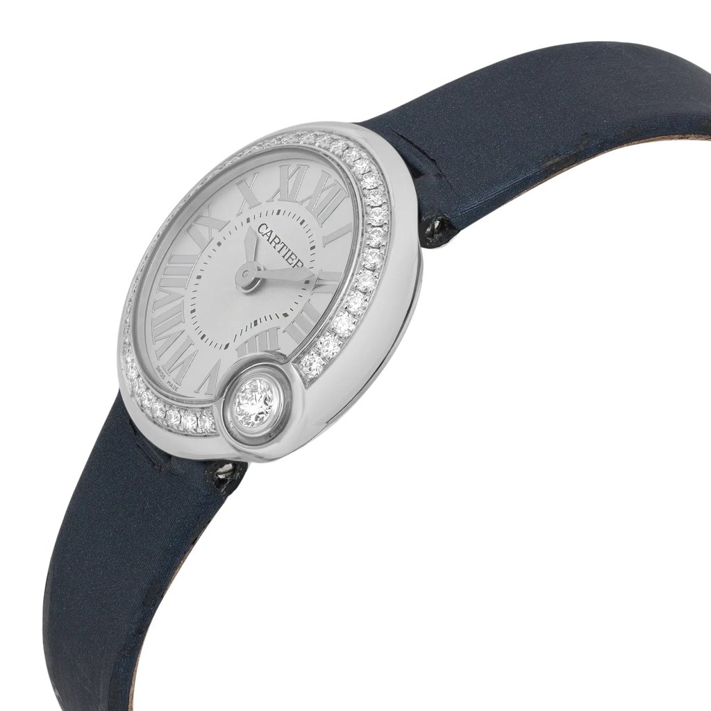 An image of a pre-owned Cartier women's wristwatch positioned at a slight angle. The watch face displays Roman numerals and is adorned with a sparkling diamond bezel. The elegant timepiece features a dark strap and is photographed from a close distance, highlighting its luxurious details and craftsmanship.
