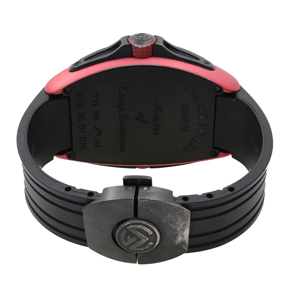 An image of a pre-owned wristwatch viewed from the back. The focus is on the closed clasp, which shows signs of wear. The watch case has a red edge, and engraved details are visible on the back plate. The angle is slightly elevated, providing a clear view of the clasp and the surrounding watch band.