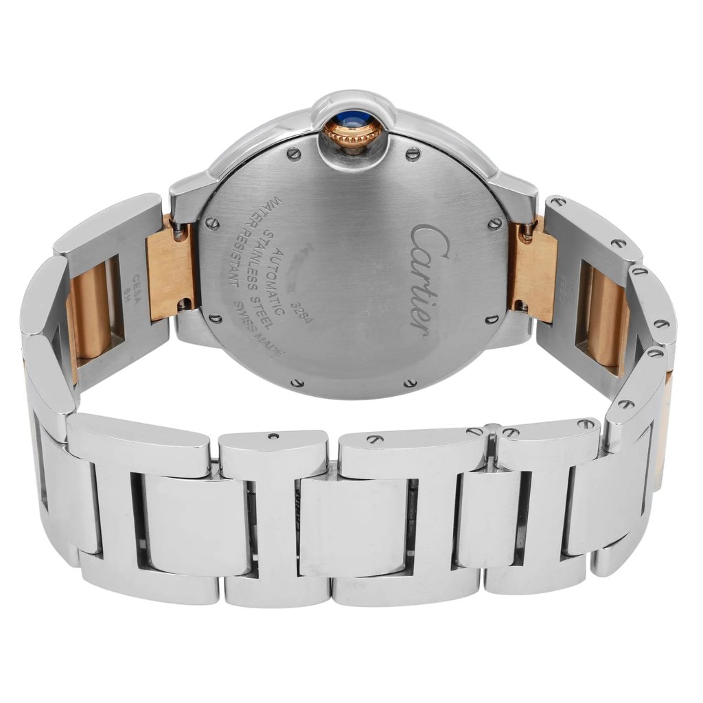 An image of a pre-owned wristwatch showing the back view with a close clasp. The watch has a stainless steel and gold-toned bracelet. The round case features a blue cabochon crown, and the back is engraved with brand details. The angle captures the watch from a close distance, highlighting its metallic finish and clasp design.