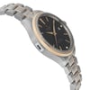 An image of a wristwatch in an unworn condition, captured from a side profile view opposite the crown. The watch features a sleek metal case with a two-tone band, blending silver and gold elements. The angle highlights the smooth contours of the case and the bracelet's links, with the face of the watch partially visible, showing a dark dial. The photograph is taken from a close distance, showcasing the watch's elegant design and craftsmanship.