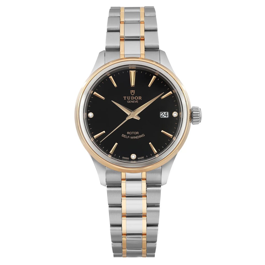 An image of a Tudor Style 28mm women's wristwatch, shown in a front-facing position. The watch is unworn and features a black diamond dial with gold hour markers and hands, including a date indicator at the 3 o'clock position. The casing is steel with a yellow gold bezel, and the bracelet is a two-tone steel and gold design. The image is taken at a close distance, highlighting the details of the watch's design and craftsmanship.