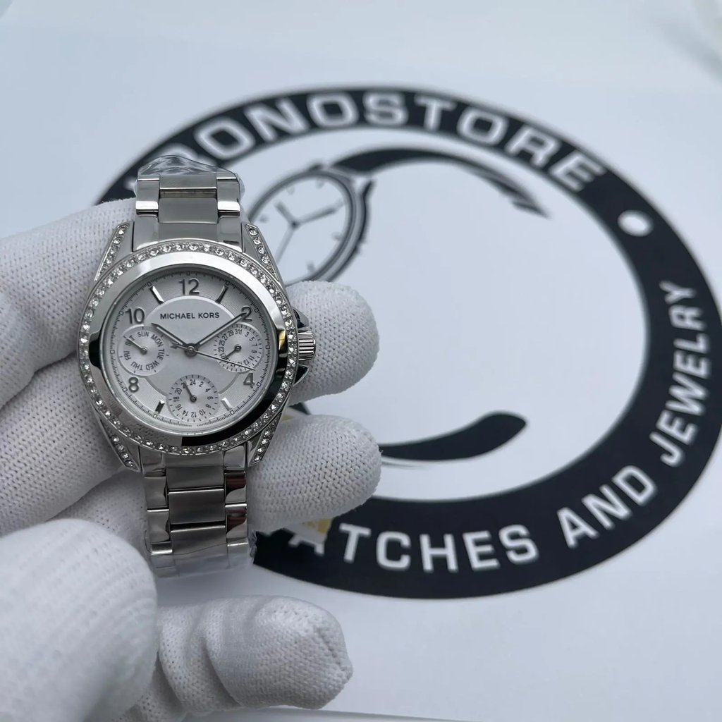 An image of a Wristwatch by Michael Kors. This Display Model item is designed for Women, featuring a Dress/Formal style. It has a Quartz movement and an Analog display with a Silver dial color. The indices include 12-Hour Dial,Arabic Numerals,Non-Numeric Hour Marks. The band is made of Stainless Steel and the case is made of Stainless Steel. The watch has a Round shape with a case size of 33 mm and a case thickness of 11 mm.