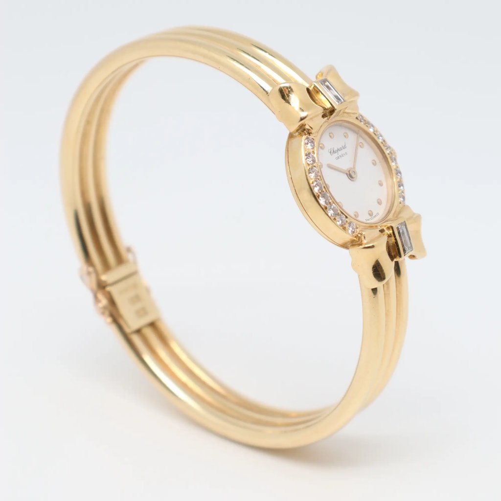 An image of a pre-owned Chopard women's wristwatch positioned at a slight angle from the front. The watch features a yellow gold band and a round face surrounded by small, sparkling diamonds. The photo is taken from a close distance, highlighting the elegant design and fine details of the timepiece.