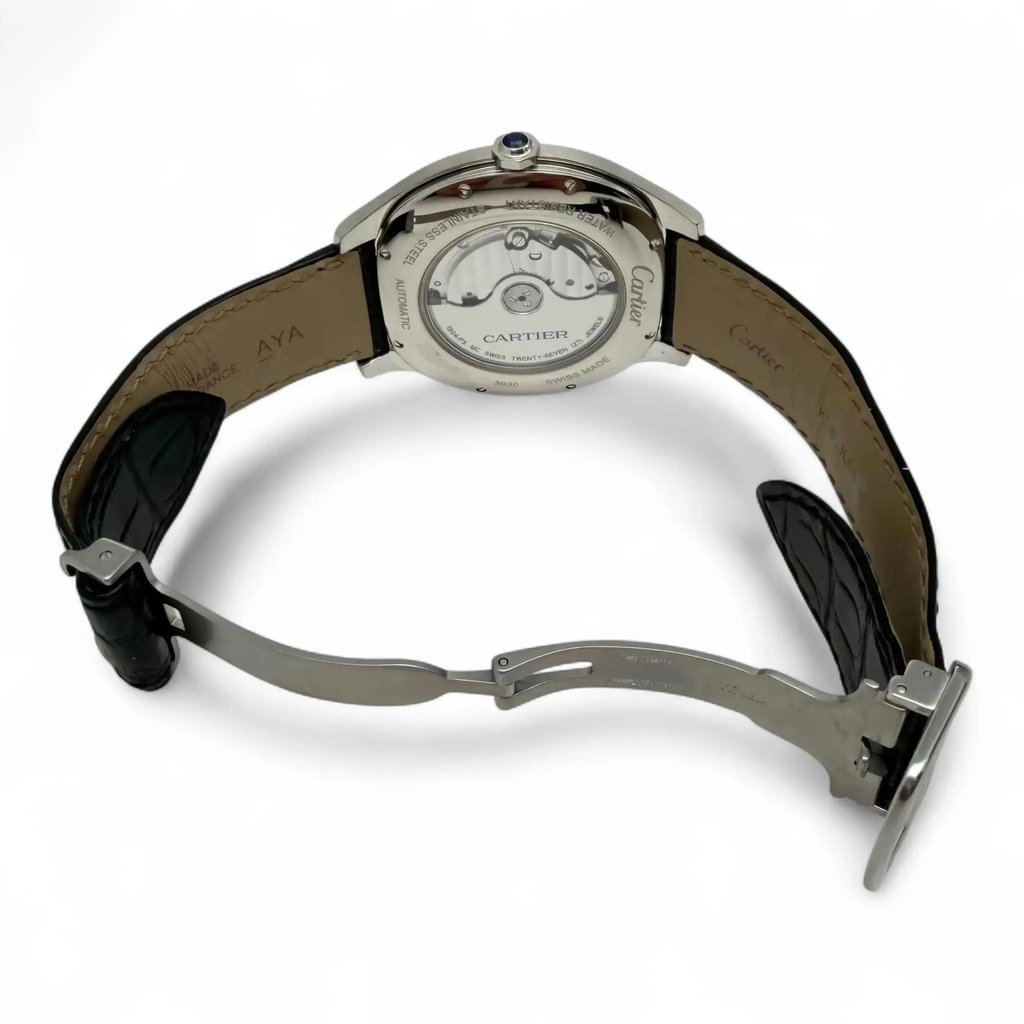 An image of a pre-owned Cartier men's wristwatch positioned at a slight angle from the back, showcasing the intricate mechanical components through the transparent case back. The watch is displayed with its black leather strap partially open, revealing the clasp and the inner side of the strap. The photograph is taken from a close distance, highlighting the watch's craftsmanship and detailing.
