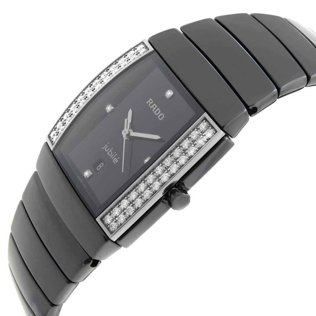An image of a pre-owned wristwatch, viewed from a side profile angle that highlights the crown. The watch features a sleek black band with a rectangular face. The edges of the watch case are adorned with sparkling stones, and the brand name is visible on the dial. The angle gives a clear view of the watch's elegant design, capturing it up close.