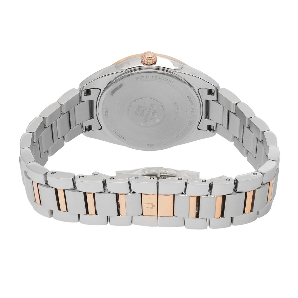 An image of a new Bulova women's wristwatch with a stainless steel band featuring rose gold-tone accents. The watch is photographed from the back, displaying the snap caseback and the closed fold-over clasp with double push buttons. The image is taken at a close distance, with the watch positioned at an angle that shows a side view of the clasp mechanism and a partial view of the watch's round case.