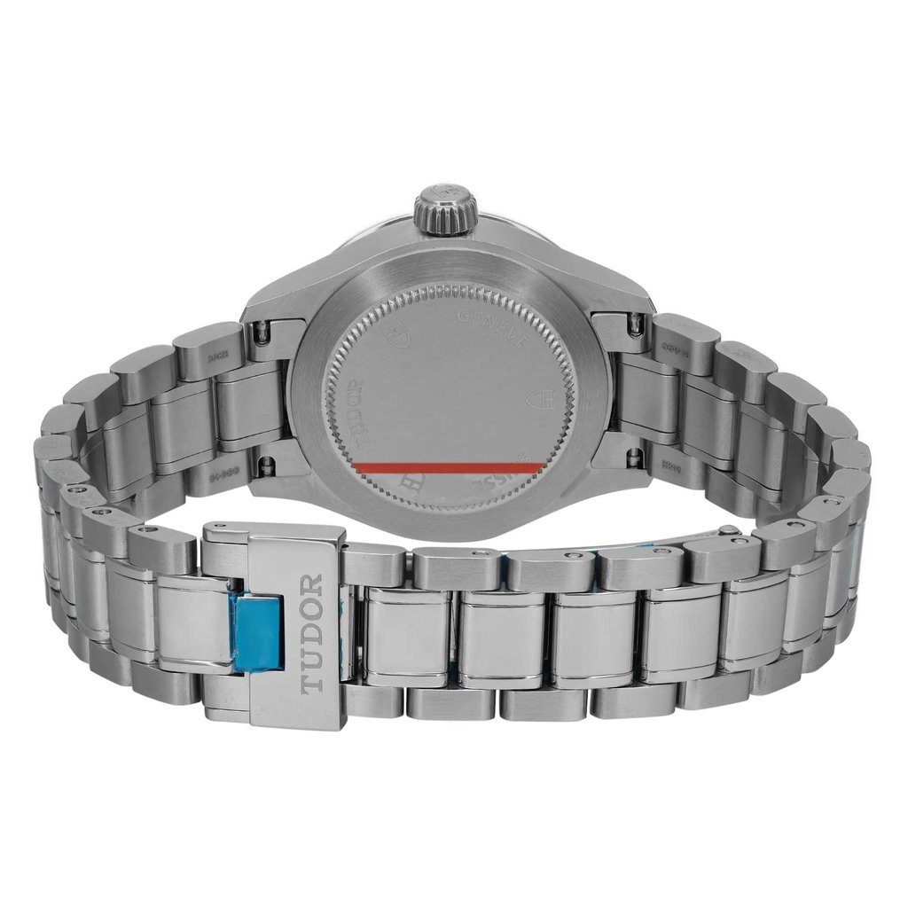 An image of a wristwatch shown from the back view, focusing on the closed clasp. The watch is unworn and has a polished metal bracelet. The clasp displays the brand name "TUDOR." The image is taken at a close distance, highlighting the details of the bracelet links and the watch case back.