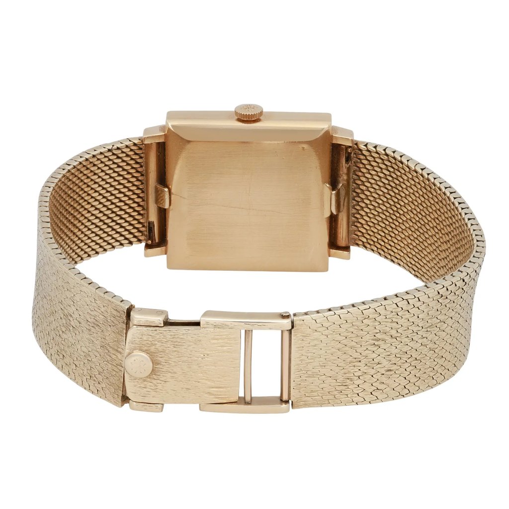 An image of a pre-owned Patek Philippe unisex wristwatch, viewed from the back. The watch is centrally positioned and captured from a straight angle at a close distance. It features a yellow gold metal bracelet with a textured pattern and a square case. The clasp is visible in the foreground, showcasing its secure fastening mechanism.