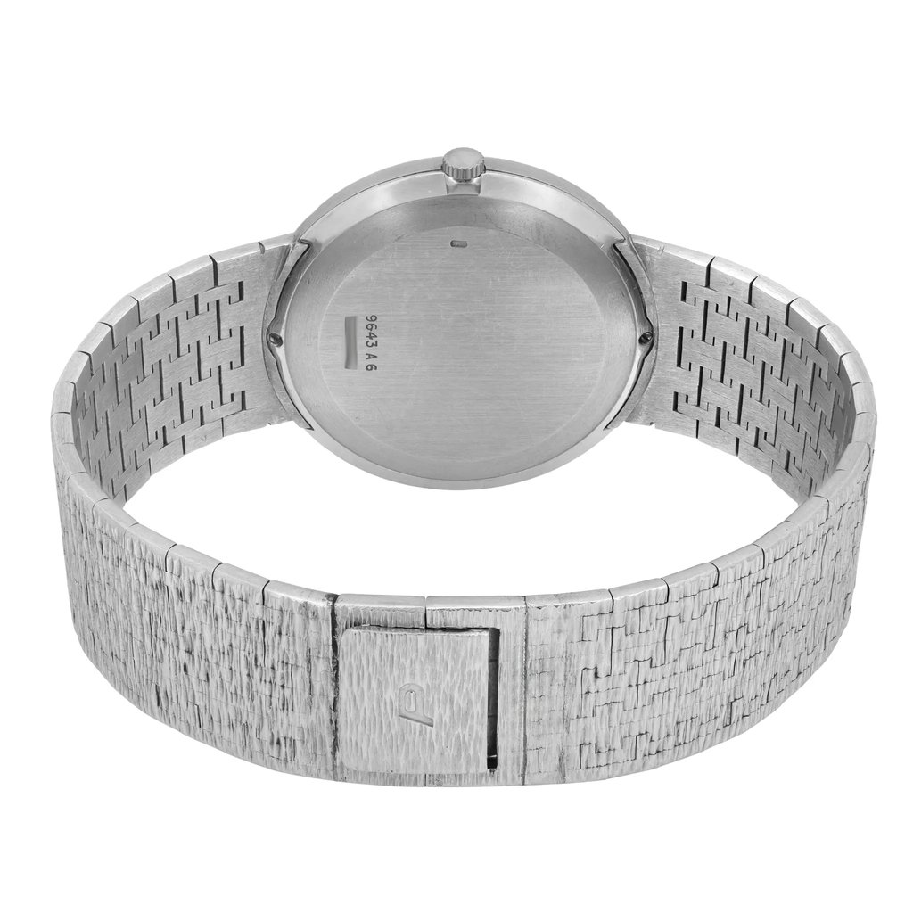 An image of a pre-owned Piaget unisex adult wristwatch taken from a slightly elevated angle, showcasing the back of the watch. The focus is on the closed stainless steel bracelet, which displays a textured pattern. The watch's round case and crown are visible, with the clasp engraved with a subtle "P" logo. The angle offers a clear view of the watch's back, highlighting its craftsmanship.