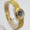 An image of a pre-owned Audemars Piguet women's wristwatch. The watch is positioned at a slight angle, showcasing its elegant design. It features a yellow gold bracelet with a polished, woven pattern. The round watch face has a onyx dial surrounded by a sparkling bezel with diamonds embellishments. The watch is displayed on a transparent stand, captured from a close distance, highlighting its luxurious details.