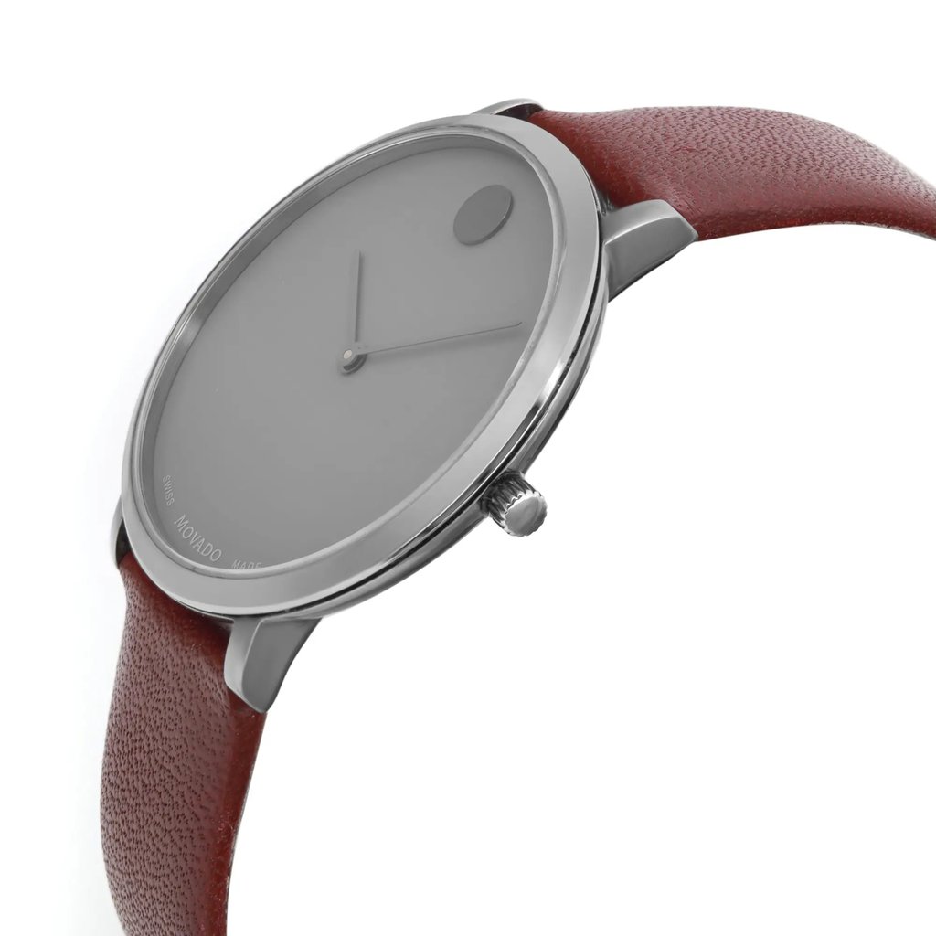 An image of a pre-owned wristwatch viewed from the side profile, showcasing the crown prominently. The angle highlights the sleek, round watch face and the smooth, brown leather strap. The photograph is taken from a close distance, emphasizing the minimalist design and polished metal casing.