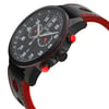 An image of a men's COVER wristwatch taken from a slightly elevated angle, showcasing the side profile and face of the watch. The watch features a black case with red accents, visible chronograph buttons, and a black strap with red stitching. The dial displays a chronograph, date indicator, and small seconds subdial, with luminous hands for enhanced visibility. The angle highlights the watch's sporty design and detailed features.