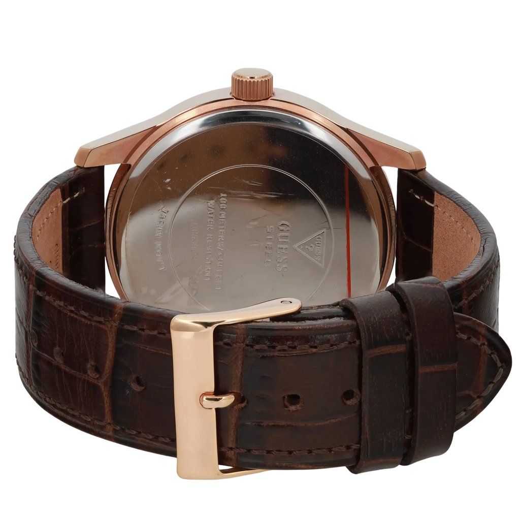 An image of a pre-owned men's GUESS wristwatch, captured from a rear angle. The focus is on the watch's back, highlighting the metallic case and engraved details. The watch is positioned upright, with the brown leather strap and gold-toned buckle prominently displayed in the foreground. The image is taken at a close distance, showcasing the texture and craftsmanship of the strap and case.