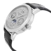 An image of a pre-owned wristwatch captured from a side profile view. The watch is positioned at a slight angle, showcasing the crown prominently. The case appears metallic with a polished finish, and the watch face includes multiple sub-dials and Roman numeral hour markers. The black leather strap is partially visible, enhancing the elegant design. The photo is taken at a close distance, highlighting the intricate details of the watch.