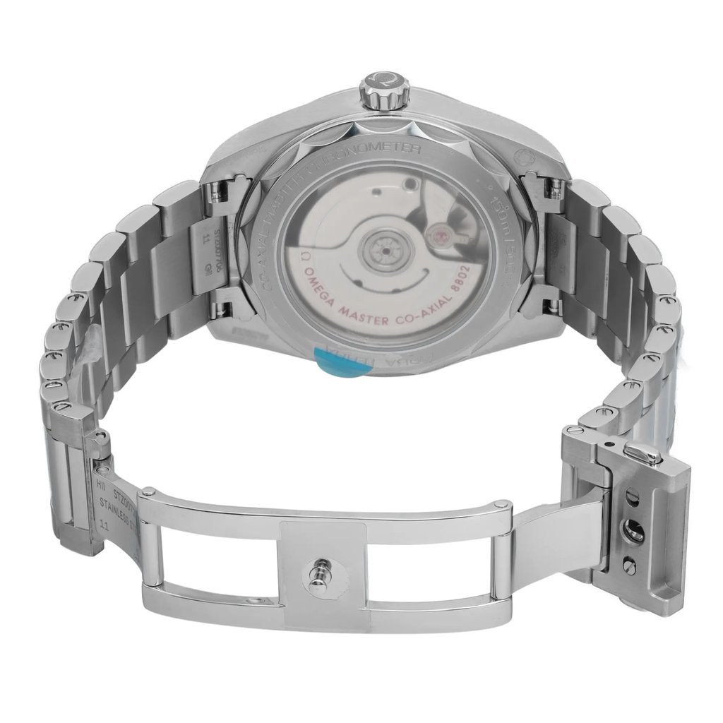 An image of a wristwatch taken from the back view, showcasing the mechanism through a transparent case back. The watch is positioned upright with an open clasp, displaying the stainless steel bracelet at a close angle. The condition appears unworn, highlighting the polished finish and intricate details of the watch's movement.