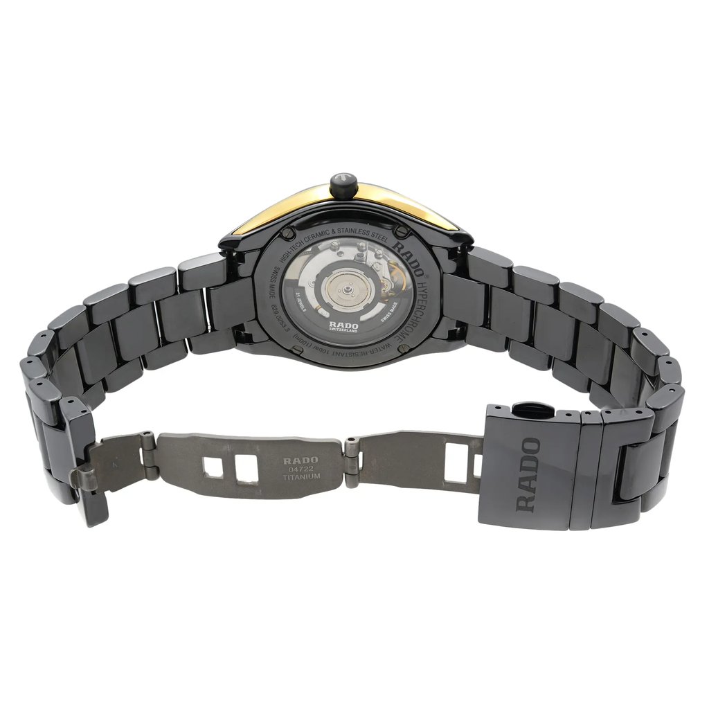 An image of a pre-owned wristwatch showing the back view with an open clasp. The watch is positioned centrally with the bracelet spread out, revealing the inner mechanism through a transparent case back. The angle is straight-on, capturing the entire back side of the watch from a moderate distance. The clasp displays the brand name "Rado" and is made of titanium.