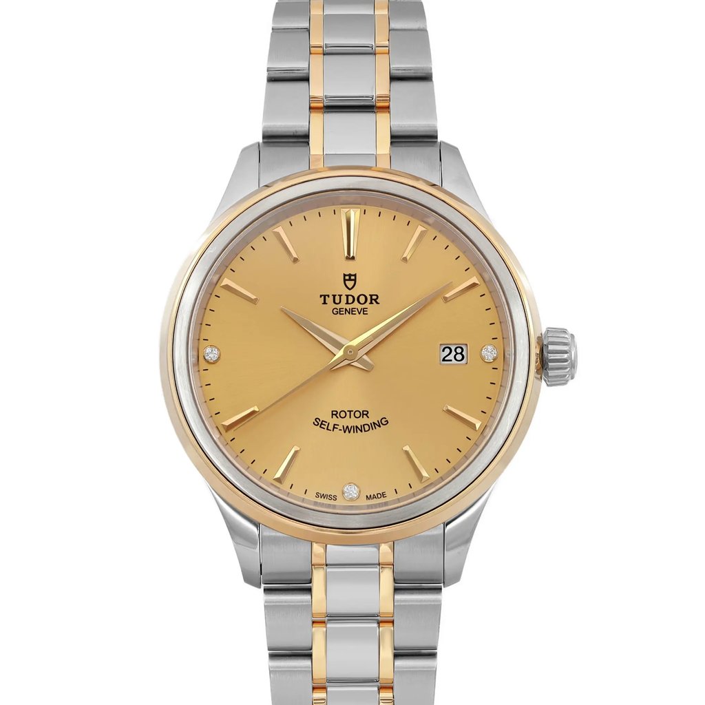 An image of a wristwatch taken from a front close-up angle, showcasing the watch face. The watch features a gold-toned dial with gold hour markers and hands. The stainless steel and gold bracelet is partially visible, emphasizing the unworn condition. The date window is positioned at 3 o'clock, and the brand name is displayed prominently on the dial.