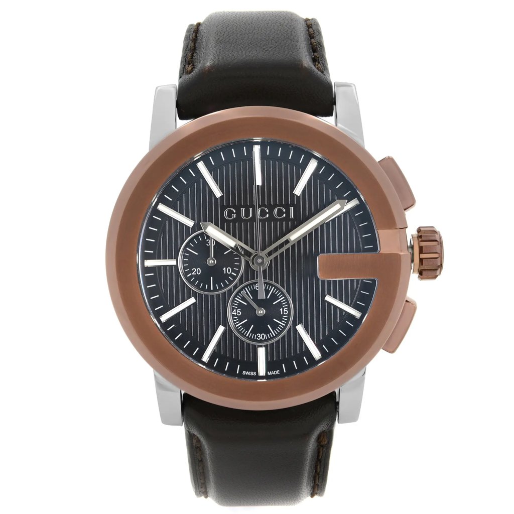 An image of a new Gucci men's wristwatch with defects, presented in a front full frontal view. The watch features a round stainless steel case with a bronze bezel and a black teaked dial. The dial includes stick indexes, a 12-hour display, a chronograph with luminous hands, and a small seconds subdial. It is fitted with a black leather band. The watch is positioned centrally and shot at a direct angle, capturing its full face with no obstructions, allowing a clear view of its details. The distance is close enough to show fine details while displaying the entire watch.
