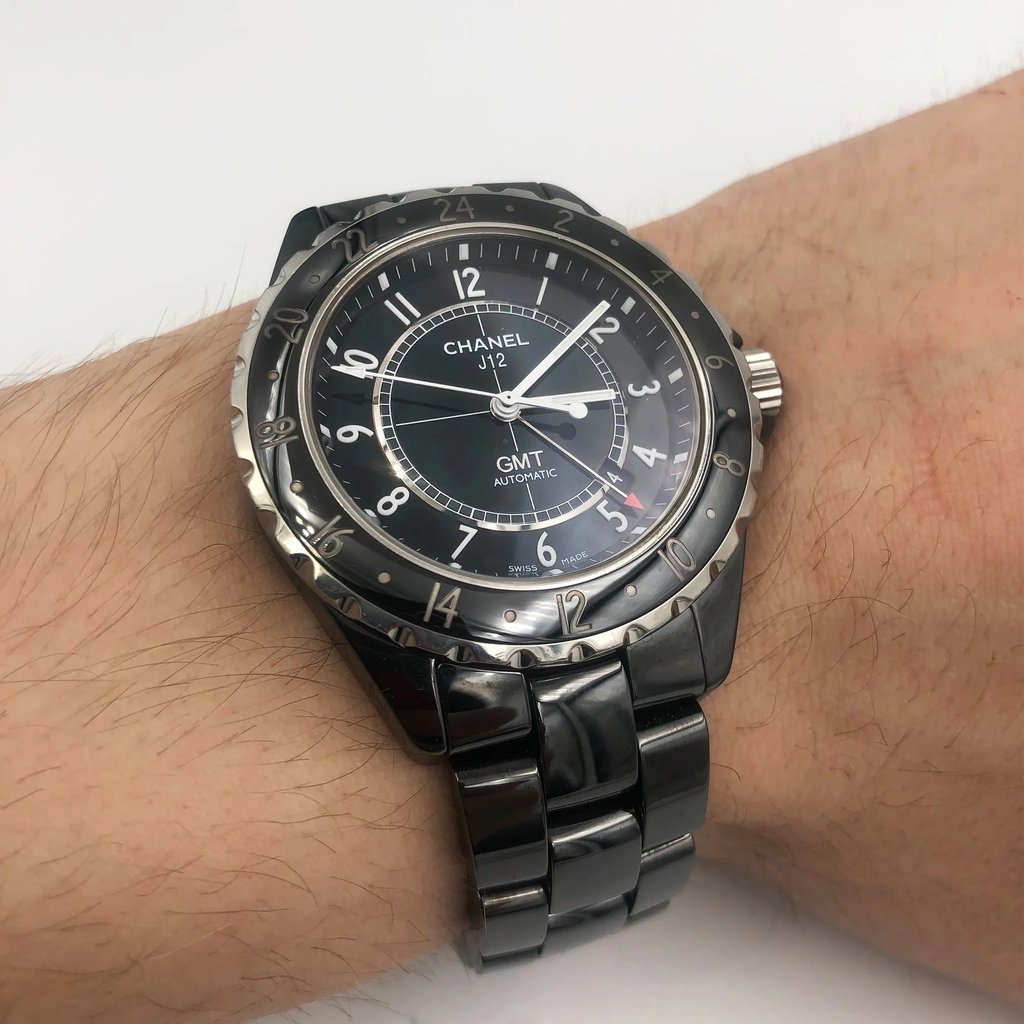 An image of a pre-owned wristwatch taken from a front full-frontal view. The watch is worn on a wrist and features a glossy black dial with silver accents and numerals. The metal bracelet and bezel complement the watch's elegant design. The photograph captures the watch at a close distance, showcasing its details clearly.
