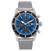 An image of a pre-owned Breitling men's wristwatch presented in a full frontal view. The watch features a round stainless steel case with minor nicks, a black bezel insert with visible scratches, and a sunburst blue dial with stick indexes for the hours. It has a chronograph function with three subdials and a date indicator at the 3 o'clock position, luminous hands, and a small seconds subdial. The stainless steel band is made of a mesh-like material. The watch is in fair condition, showing signs of wear consistent with its pre-owned status. The image is taken from a medium distance, showing the watch head-on with its entire face and part of the band visible.
