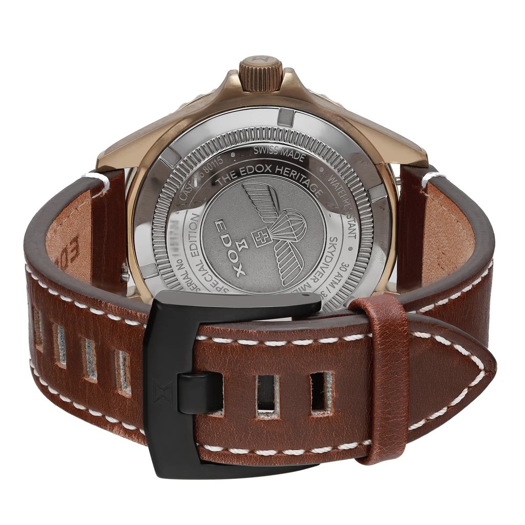 An image of a pre-owned wristwatch, shown from the back view. The focus is on the closed clasp and the detailed inscriptions on the case back. The brown leather strap with white stitching is visible in the foreground. The angle is slightly elevated, providing a clear view of the watch's back at a close distance.