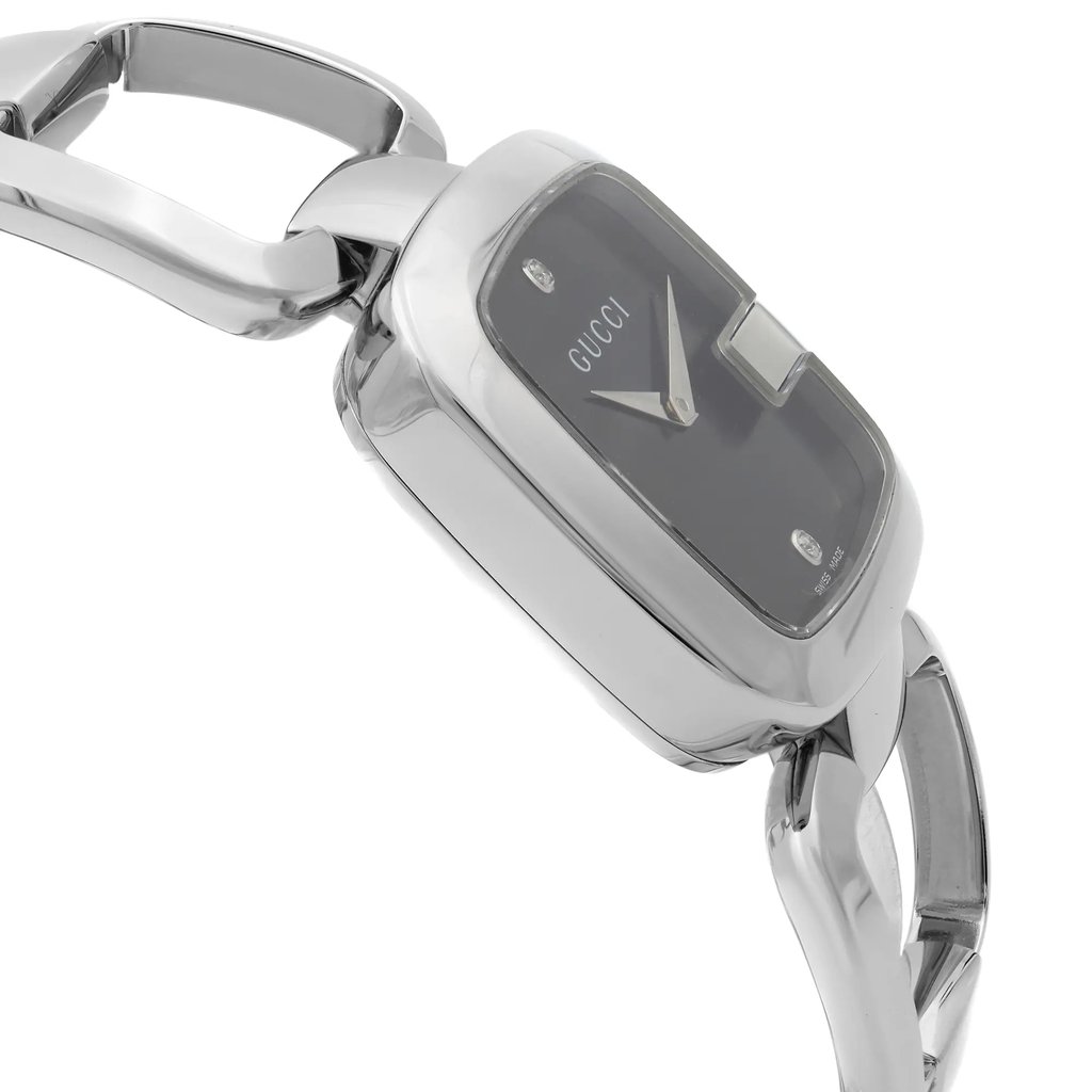 An image of a pre-owned Gucci wristwatch for women, focused on the side profile opposite the crown. The watch has a round shape with a silver stainless steel case and band. It features a black sunburst pattern dial under a clear, reflective surface with the Gucci logo displayed at the center top. The bezel color is silver, complementing the overall dress/formal style. The watch is shown at a close distance and a slight angle, highlighting its side profile and the curvature of the links on the band.