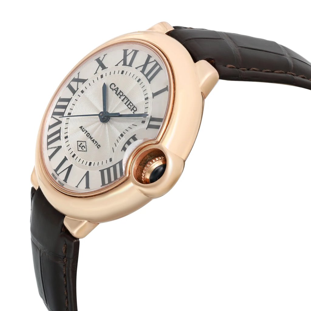 An image of a pre-owned wristwatch viewed from the side profile, showcasing the crown prominently. The watch features a round face with Roman numerals and a detailed dial. The casing is a polished metallic tone, and it is paired with a dark leather strap, visible from a close angle.