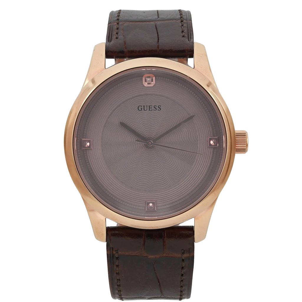 An image of a pre-owned men's GUESS wristwatch. The watch is positioned upright with a frontal view, displaying its round face and gold-tone casing. The dial is a subtle pattern with minimalistic hour markers and hands. The watch has a brown leather strap, textured to resemble alligator skin, and the crown is visible on the right side. The photograph is taken straight-on at a close distance, capturing the details of the watch face and strap.