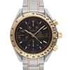 An image of a pre-owned men's OMEGA wristwatch, captured from the front in a close-up shot. The watch features a round, black dial with gold stick indexes and a gold bezel. It includes a chronograph, date indicator, luminous hands, and a small seconds subdial. The stainless steel band complements the case, and the condition is classified as good.