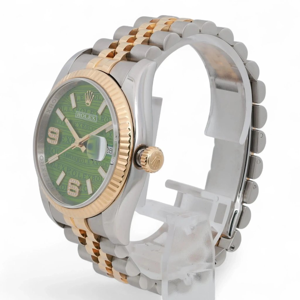 An image of a pre-owned unisex Rolex wristwatch positioned at a slight angle. The watch features a green dial with luminous hands, a date indicator, and a two-tone metal bracelet. The photo is taken from a close distance, showcasing the gold bezel and the brand logo on the crown.