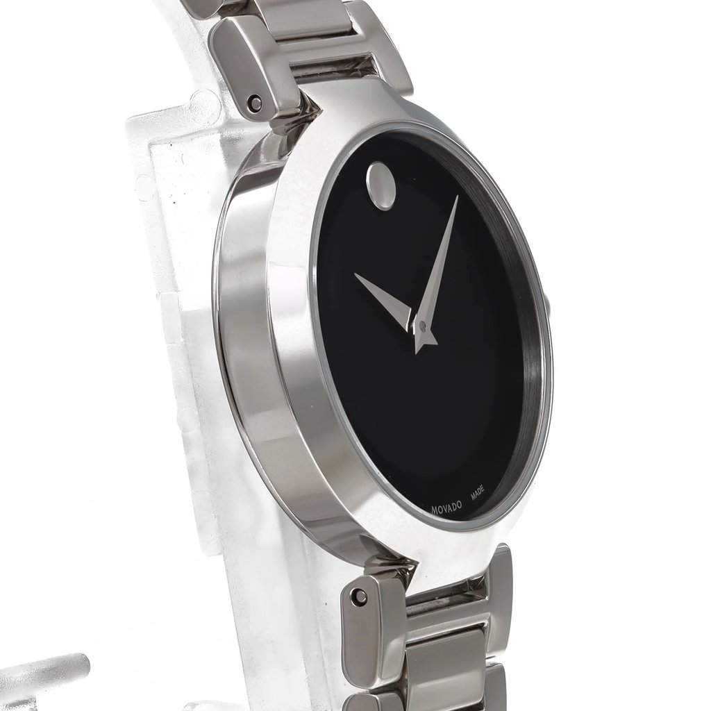 An image of a wristwatch captured from a side profile view, opposite the crown. The watch is positioned at a slight angle, showcasing its sleek metallic case and bracelet. The face of the watch is black with minimalist design elements. The photo is taken at a close distance, highlighting the watch's polished finish, typical of a display model.