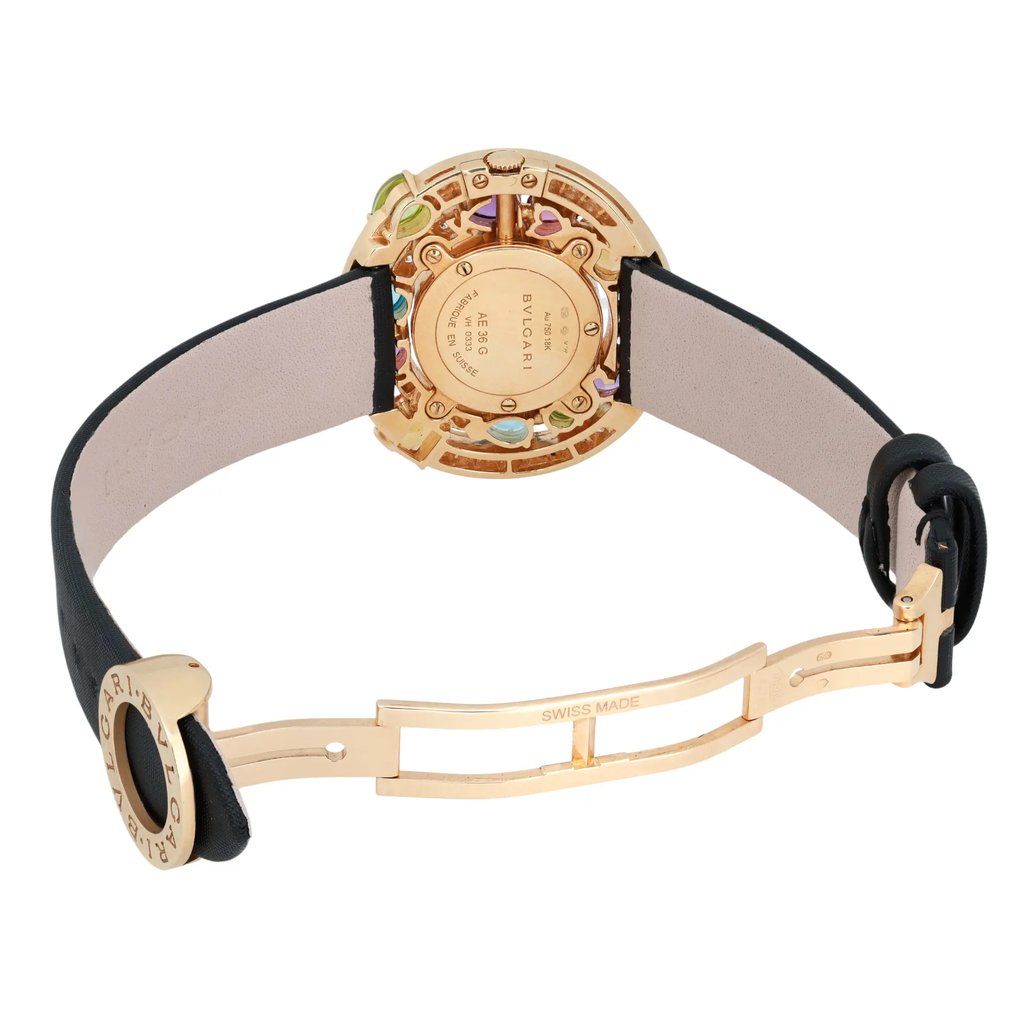 An image of a pre-owned Bvlgari women's wristwatch taken from the rear at a slight angle, showcasing the open clasp and the intricate back design. The watch has a gold-toned case with multicolored accents and a black leather strap, positioned centrally and viewed from a moderate distance to capture details.