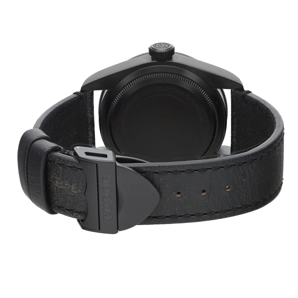 An image of a wristwatch viewed from the back, showcasing the closed clasp. The watch has a dark leather strap and a black case. The angle is straight on, focusing closely on the clasp and the case back. The watch is in display model condition.