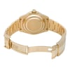 An image of a pre-owned men's Rolex wristwatch viewed from the back. The watch is positioned on a flat surface, with the bracelet open and extended. The focus is on the case back and clasp, showcasing the gold finish and detailed engravings. The angle captures the watch from a slightly elevated perspective, providing a clear view of the back and internal clasp markings. The distance is close, emphasizing the watch's craftsmanship and condition.