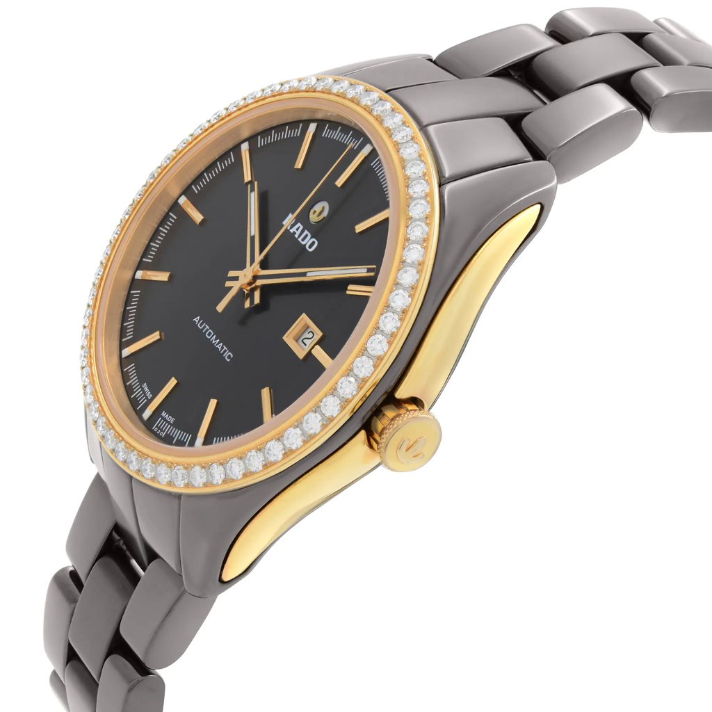 An image of a wristwatch taken from a side profile view, showcasing the crown prominently. The watch features a metallic band with a polished finish, and the face is adorned with a diamond-encrusted bezel. The watch's condition is that of a display model. The angle and distance highlight the luxurious details and craftsmanship of the timepiece.