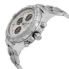An image of a pre-owned wristwatch taken from a side profile view at a close angle. The focus is on the watch's crown, showcasing its intricate design. The watch has a silver metal bracelet and a detailed bezel. The face of the watch, partially visible, features multiple sub-dials.