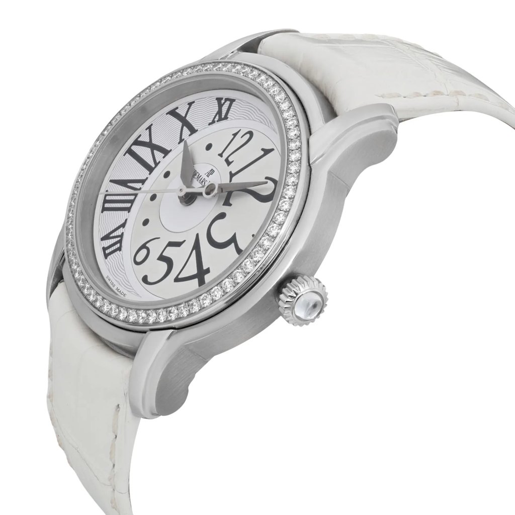 An image of a pre-owned women's Audemars Piguet wristwatch, angled slightly from the right side, showcasing its elegant design. The watch features a round silver-tone case with a diamond-encrusted bezel, a white dial with large black numerals, and a white leather strap. The watch is positioned at a close distance, highlighting its intricate details and luxurious appearance.