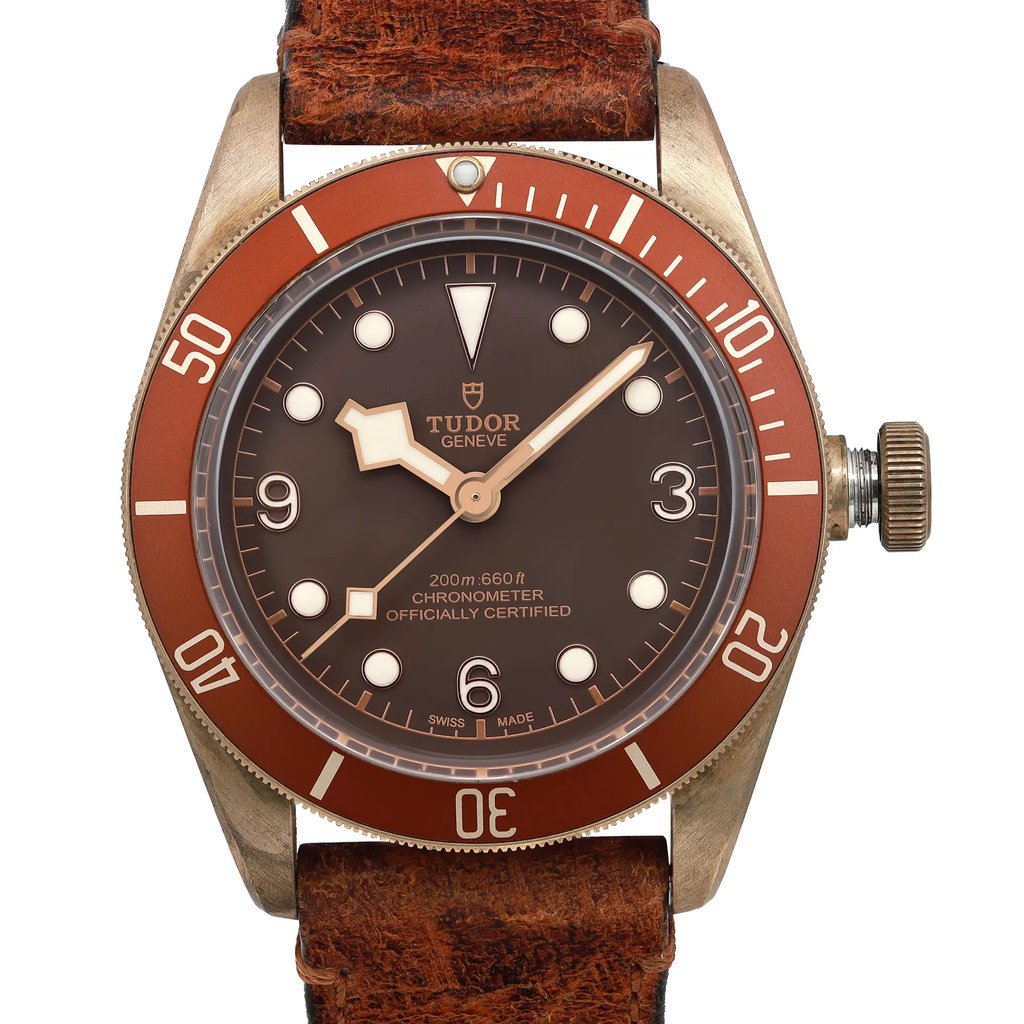 An image of a Wristwatch by TUDOR. This Pre Owned item is designed for Men, featuring a Luxury style. It has a Mechanical (Automatic) movement and an Analog display with a Brown dial color. The indices include 12-Hour Dial,Arabic Numerals,Round Indexes. The band is made of Leather and the case is made of Bronze. The watch has a Round shape with a case size of 43 mm and a case thickness of 15 mm.