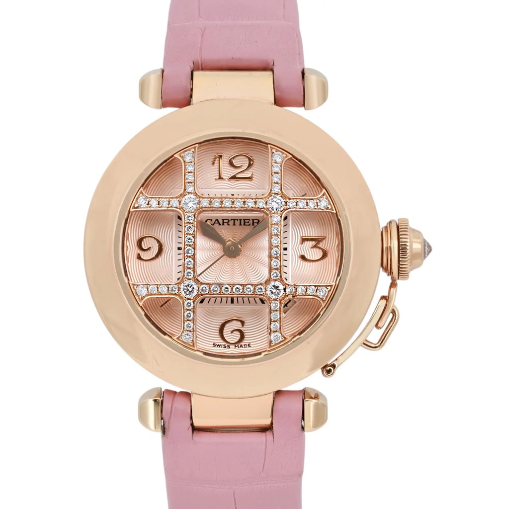 An image of a pre-owned Cartier women's wristwatch, featuring a round rose gold case with a prominent date indicator. The watch has a pink leather strap and is viewed from a front angle, showcasing the intricate dial design with diamond accents. The photo captures the watch at a close distance, emphasizing its elegant details and craftsmanship.