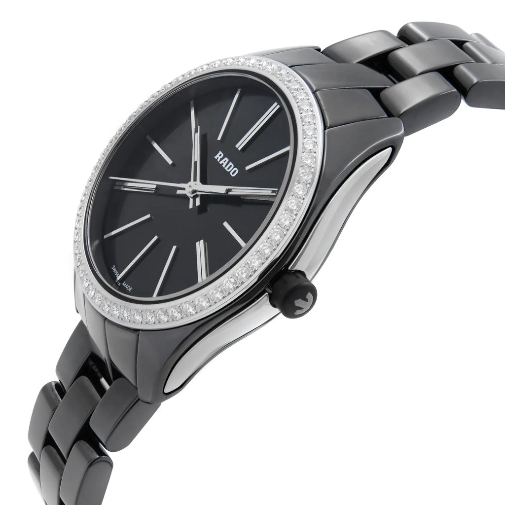 An image of a wristwatch taken from a side profile view, highlighting the crown. The watch has a sleek black face with silver hour markers and a bezel adorned with sparkling stones. The angle showcases the watch's elegant design and the polished metal bracelet. The distance is close, allowing for detailed visibility of the watch's features.