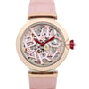 An image of a pre-owned wristwatch taken from a front close-up angle, showcasing the intricate details of the watch face. The design features a rose gold-tone bezel with a visible mechanical interior and stylized lettering. The watch hands are red, and the strap is a soft pink color.