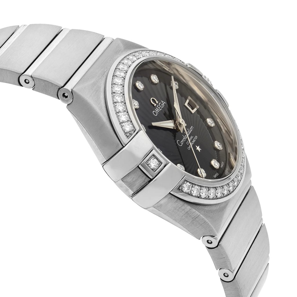 An image of an unworn OMEGA luxury wristwatch for women, featuring a side profile view opposite the crown, positioned at a slight angle to show the round watch face and the band. The watch has a black dial and is made of white gold, with the case and band exhibiting a sleek, polished surface. The bezel is adorned with a ring of sparkling diamonds. The watch is captured close-up, emphasizing its details and craftsmanship.