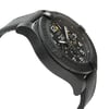 An image of a wristwatch viewed from the side profile, opposite the crown. The watch is positioned at a slight angle, showcasing its sleek, black case and textured strap. The face of the watch displays detailed markings and hands, indicating it is a display model. The image is taken from a close distance, highlighting the intricate details of the timepiece.