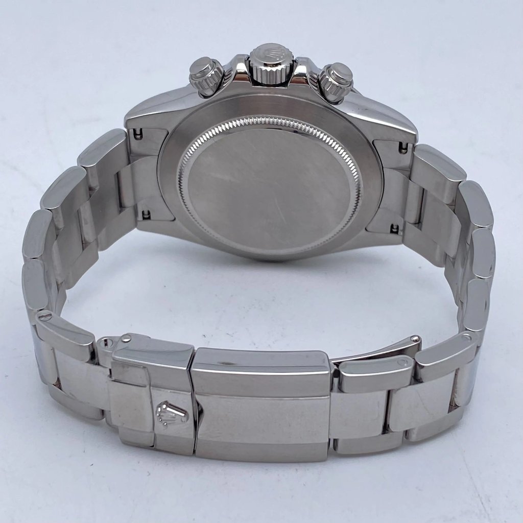 An image of a pre-owned men's Rolex wristwatch positioned with the back case facing upward. The watch is angled slightly from behind, showcasing the stainless steel bracelet and the clasp with the Rolex logo visible. The image is taken from a close distance, highlighting the smooth, polished surfaces and the watch's chronograph features.