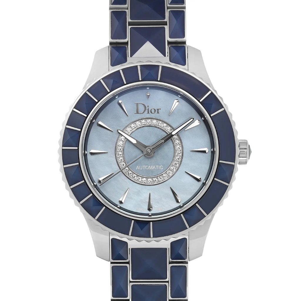 An image of a wristwatch, captured in a front close-up shot, highlighting the watch face. The watch is a display model with a polished design, featuring a light blue dial with silver-tone hands and hour markers. The bezel and bracelet are adorned with dark blue geometric patterns, adding a sophisticated contrast. The brand name is elegantly displayed on the dial.