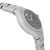An image of a pre-owned wristwatch shown from a side profile view, opposite the crown. The watch features a metallic bracelet and a round case, with a dark dial encircled by a bezel set with small stones. The photograph captures the watch at a close angle, highlighting the sleek design and detailing.