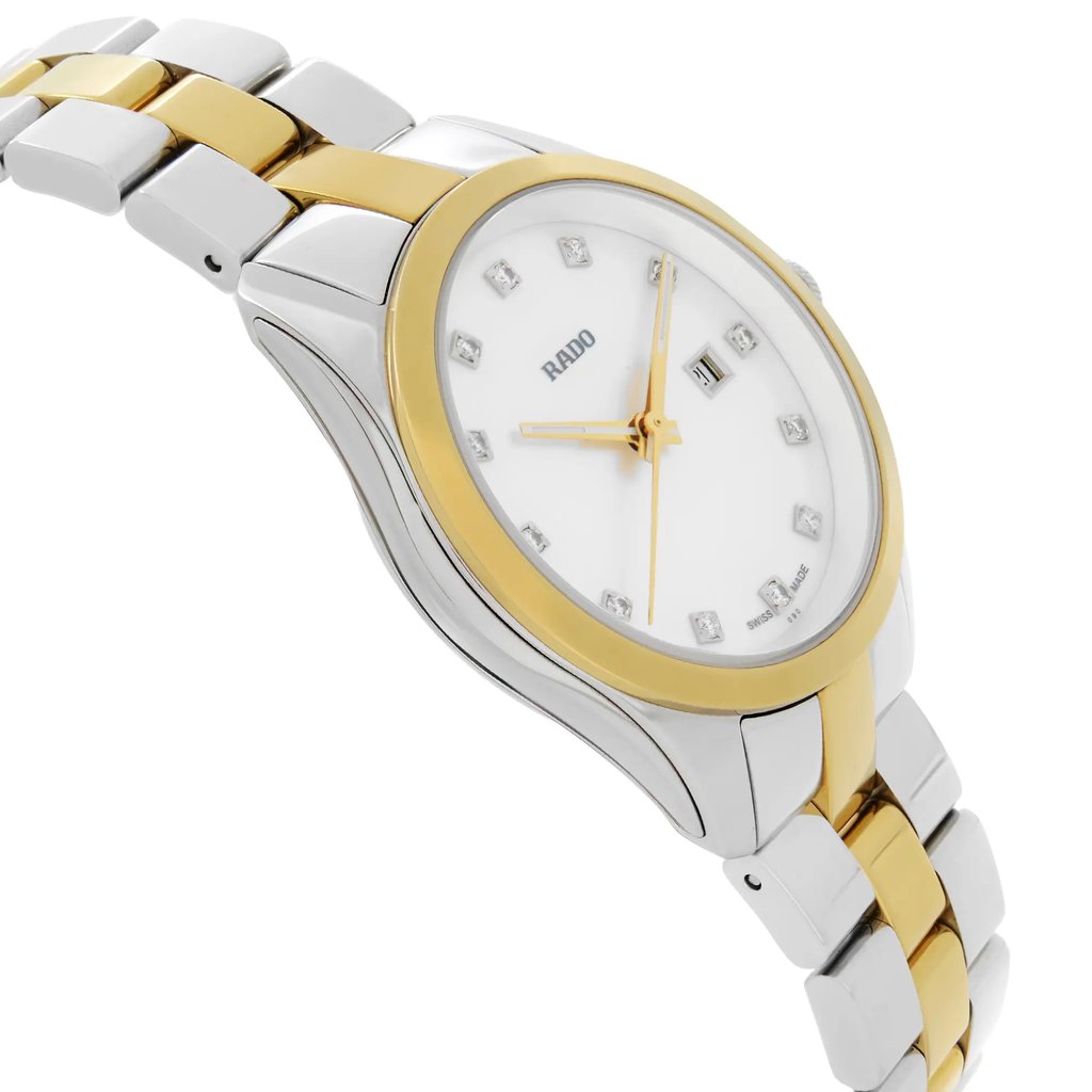 An image of a wristwatch, viewed from the side profile opposite the crown. The watch features a two-tone metal finish with a gold bezel and silver accents. The face is white with diamond hour markers, and gold-tone hands are visible. The bracelet is a combination of gold and silver links. The watch is a display model, positioned at an angle to highlight its sleek design from a close distance.