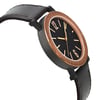 An image of a new Bvlgari men's wristwatch, positioned in a side profile view opposite the crown, displaying a black dial with a bronze bezel. The watch features a round Black DLC stainless steel case and a casual dark brown leather strap. The photo is taken from a close distance, capturing the watch from a side angle that emphasizes its sleek design and the contrast between the dial color and the bezel. The watch is unworn.