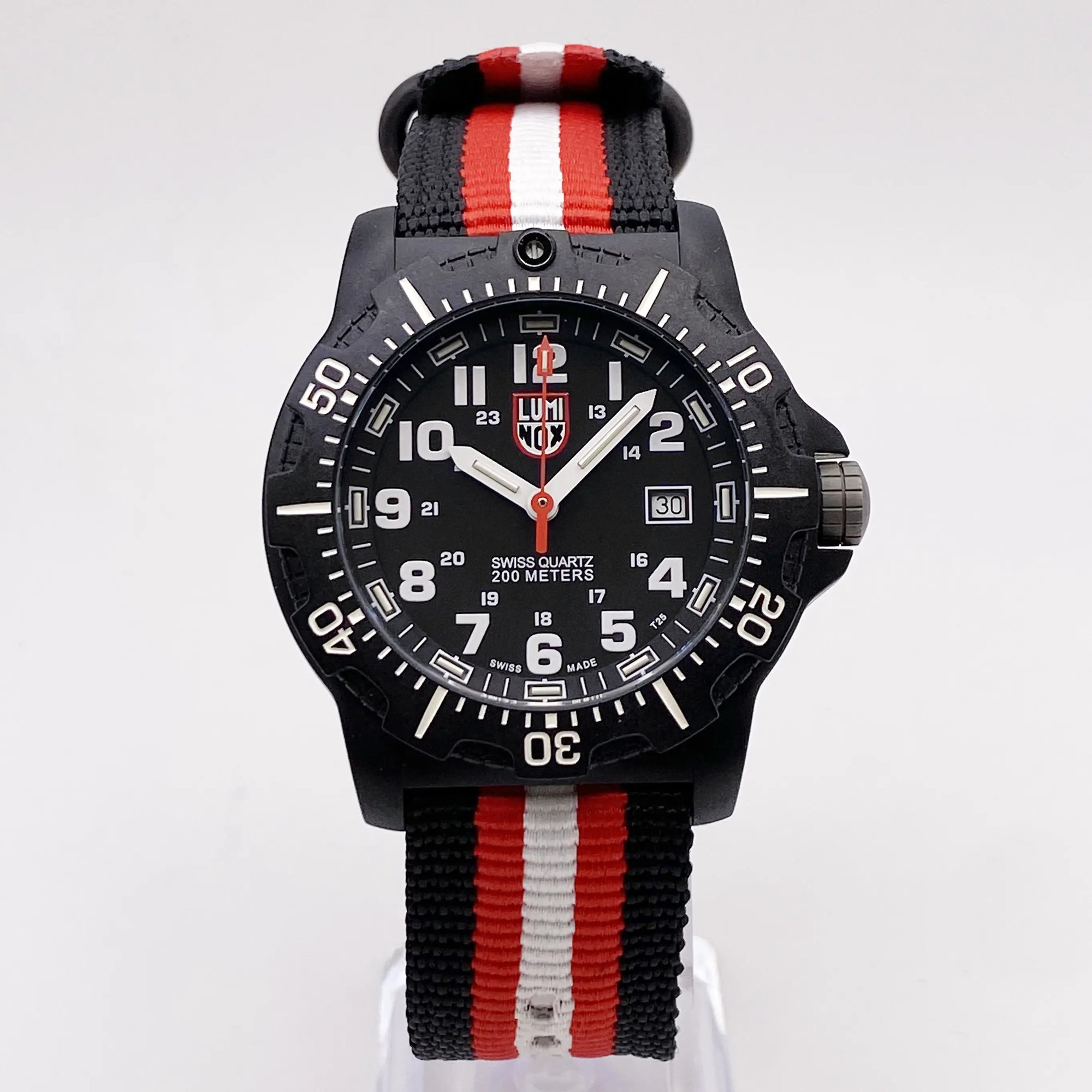 An image of a Wristwatch by Luminox. This Pre Owned item is designed for Men, featuring a Casual style. It has a Quartz movement and an Analog display with a Black dial color. The indices include 12-Hour Dial,24-Hour Dial,Easy to Read/Large Numerals. The band is made of Nylon and the case is made of Carbon. The watch has a Round shape with a case size of 45 mm and a case thickness of 13 mm.